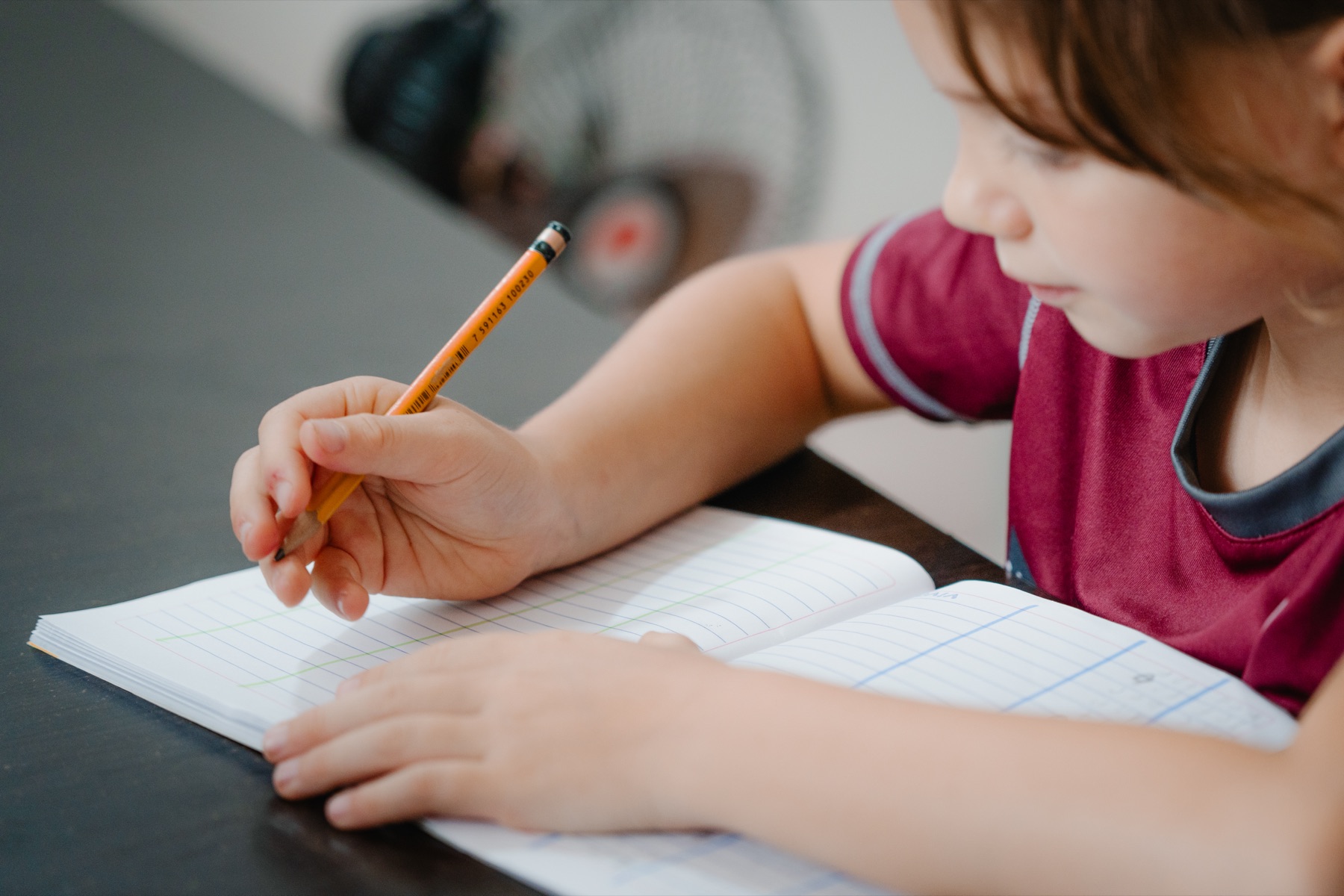 Detalle de una niña escribiendo en su cuaderno durante un ejercicio