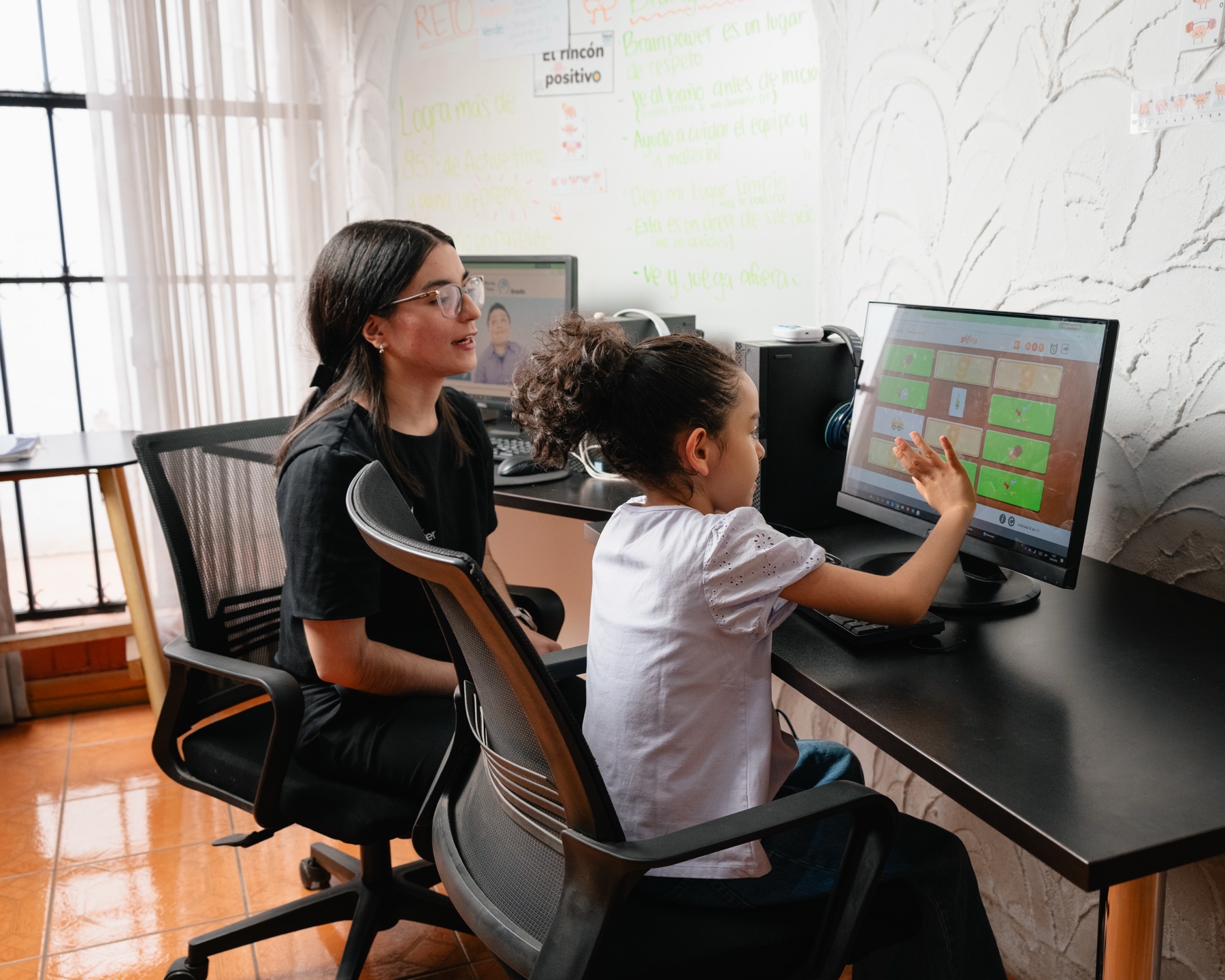 Una entrenadora y una niña revisando su resultado en pantalla